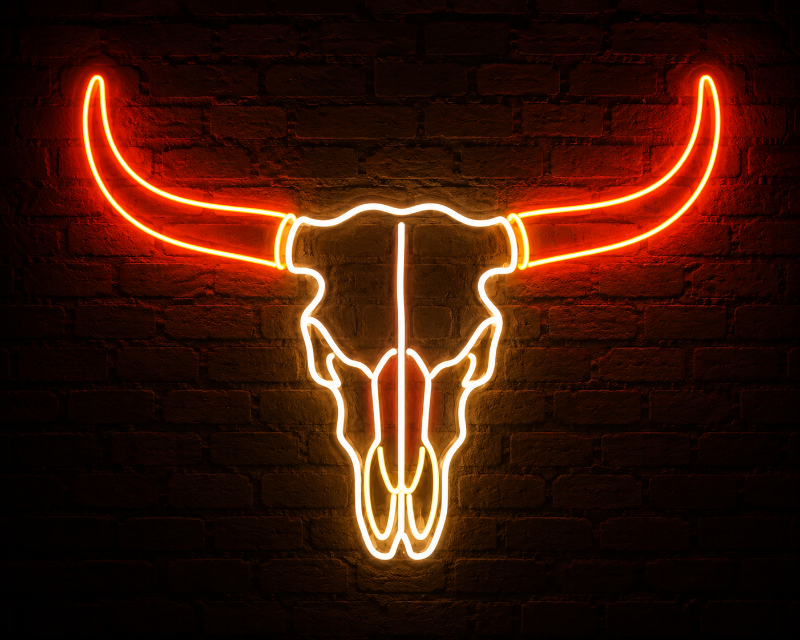 A glowing neon bull skull sign with long curved horns, illuminated in bright orange and yellow light against a dark brick wall background.