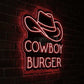 A neon sign for 'Cowboy Burger' featuring a cowboy hat outline above the words 'COWBOY BURGER' in glowing pink letters, mounted on a dark brick wall.
